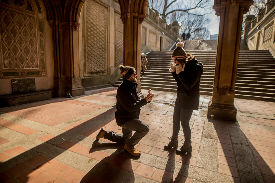 A man proposing to a women on one knee with a sapphire engagement ring © Caleb Oquendo