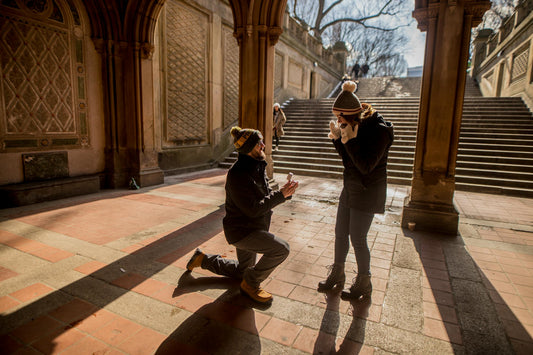 A man proposing to a women on one knee with a sapphire engagement ring © Caleb Oquendo