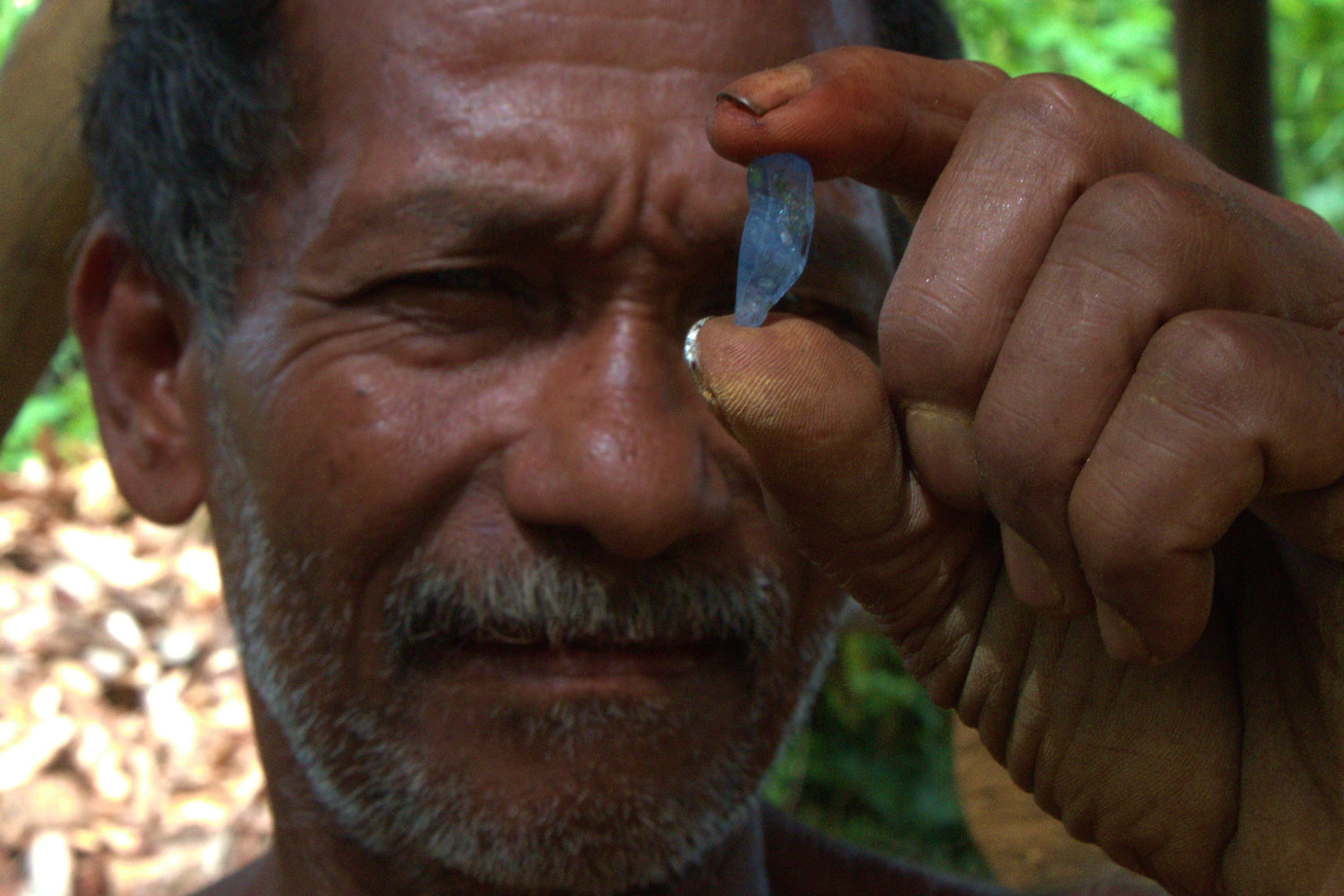 Sri Lankan gem miner with a blue sapphire crystal